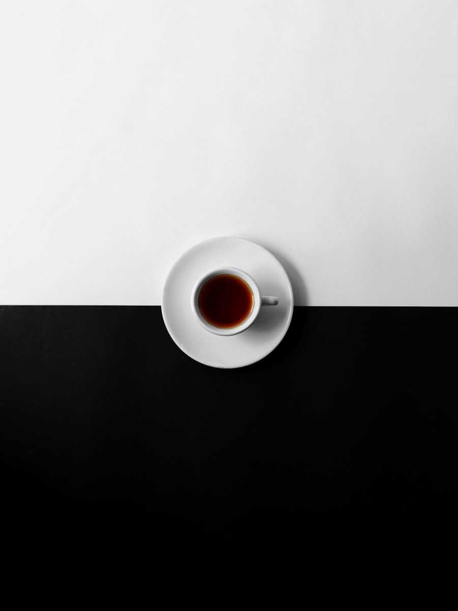 A single black coffee seen from directly above, in a white cup on a stark two-tone table